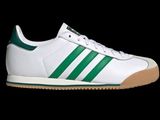une paire de baskets Adidas blanches et vertes sur fond noir