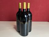 trois bouteilles de vin posées les unes à côté des autres sur un comptoir