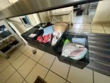 a kitchen with a stainless steel counter top and a black bin filled with food
