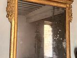 un miroir accroché au mur au-dessus d'un vase orné d'une tête de cerf