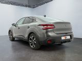 the rear end of a grey car in a white room