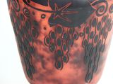 a red vase with a black design on it
