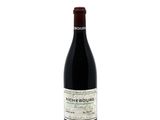 the bottle of red wine is sitting on a white surface