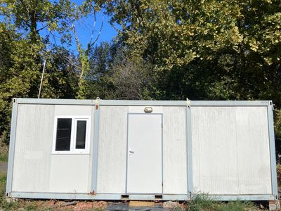 an image of a white portable home in the woods