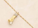 a close up of a gold necklace with a hand holding a diamond