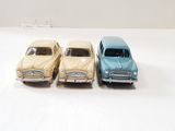 three toy cars sitting next to each other on a white surface