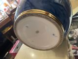 a blue vase with a gold rim sitting on top of a table