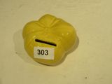 une tirelire jaune posée sur une table blanche