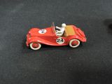 a red toy car with a man in it on a black surface