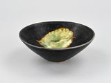 a small black bowl with a green leaf in it