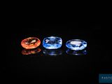 trois pierres précieuses de couleurs différentes posées sur une surface noire