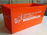une boîte orange posée sur une table, sur laquelle figure un logo