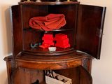 a small corner cabinet with a mirror on top of it