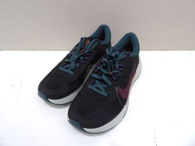 des baskets violettes et bleues posées sur une surface blanche, avec un mur blanc en arrière-plan