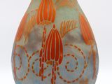 an orange and blue vase sitting on a white surface