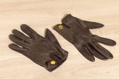 pair of brown leather gloves with buttons on a wooden surface