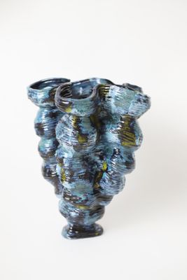 un vase bleu posé sur une surface blanche