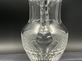 a clear glass vase with a handle on a table