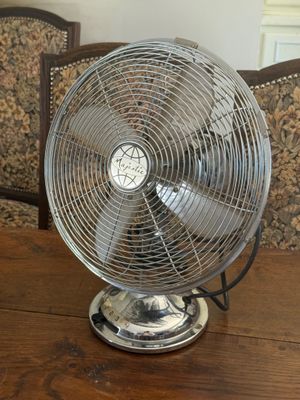 a table with a fan on it and a chair in the background
