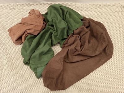 un tas de vêtements sur un lit recouvert d'une couverture blanche