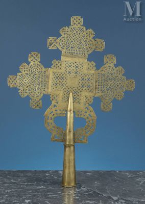 une croix en métal doré posée sur une table, sur fond bleu