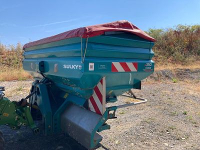 un camion-benne bleu recouvert d'une bâche rouge