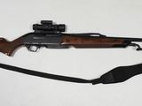 le fusil est posé sur une surface blanche, entouré d'une sangle noire