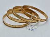 trois bracelets rigides en or, surmontés d'une étiquette
