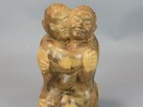 statue of two children hugging each other on a gray surface