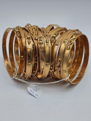 un gros plan sur une pile de bracelets en or posés sur une surface blanche