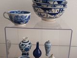 several blue and white bowls and vases are on display in a glass case