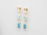 une paire de boucles d'oreilles en topaze bleue et en topaze blanche sur fond blanc