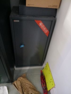 un réfrigérateur noir et un sac marron posé par terre