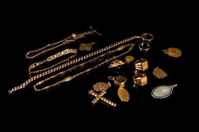 gold jewelry on a black background with a coin in the foreground