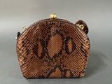 brown snake skin purse with gold accents on a gray background