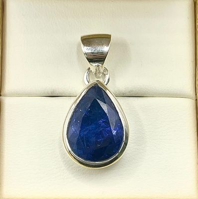 blue sapphire tear shaped pendant in a box on a white background
