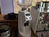 un moulin à café posé sur un plan de travail, à côté d'une cafetière