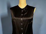 a black top on a mannequin stand against a blue wall
