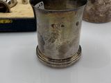 a silver cup sitting on a table next to a watch