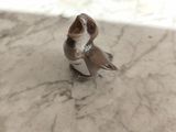 une petite figurine représentant un oiseau perché sur une table en marbre