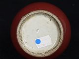 a red vase with a blue dot on it