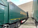 two green semi trucks parked next to each other in a parking lot