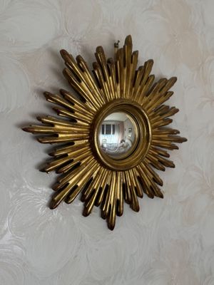 un soleil doré rayonnant accroché au mur au-dessus d'un miroir