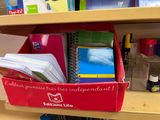 a red box filled with school supplies on a shelf