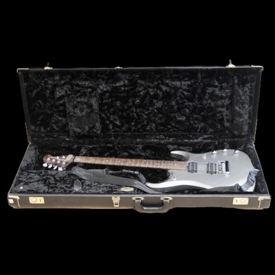 une guitare rangée dans un étui, sur fond noir
