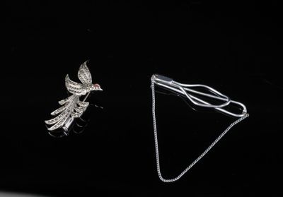 deux bijoux posés sur une surface noire, sur fond noir