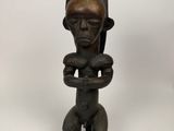 une petite statue en bois représentant un homme tenant un bébé dans ses bras
