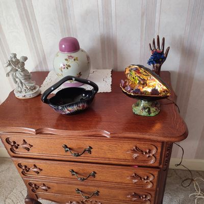a wooden chest of drawers with a vase on top of it