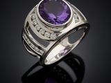 a close up of a ring with a purple stone surrounded by diamonds