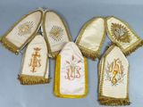 six mitaines brodées de blanc et d'or, ornées de franges dorées, sur fond bleu